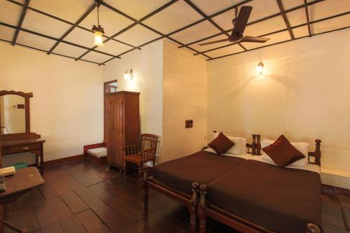 een slaapkamer met een bed en een plafondventilator bij Rossitta Wood Castle in Cochin