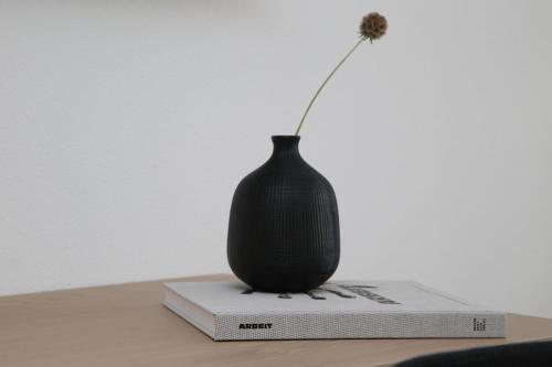 a black vase sitting on top of a book at Businesshotel Forum Widnau in Widnau