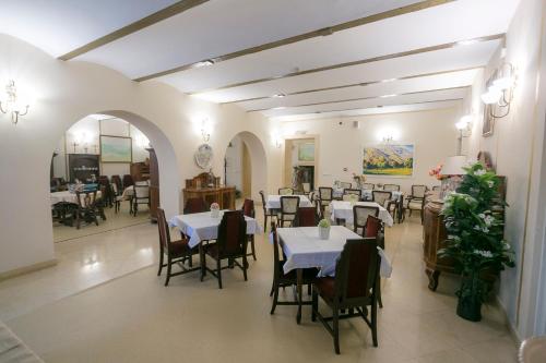una sala da pranzo con tavoli e sedie bianchi di Garni Hotel Helvetia a Belgrado