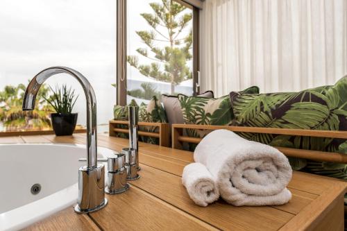ein Badezimmer mit einem Waschbecken und einer Badewanne mit Handtüchern in der Unterkunft Kalamaki Luxury Suites in Kalamaki
