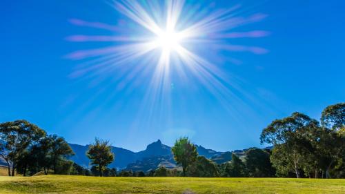 a sun in the sky over a green field at Gooderson Drakensberg Gardens Golf & Spa Resort in Drakensberg Garden