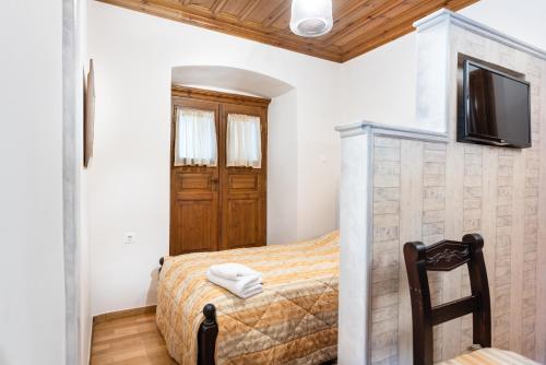 a bedroom with a bed and a tv on a wall at Kaza Guesthouse in Dhimitsana
