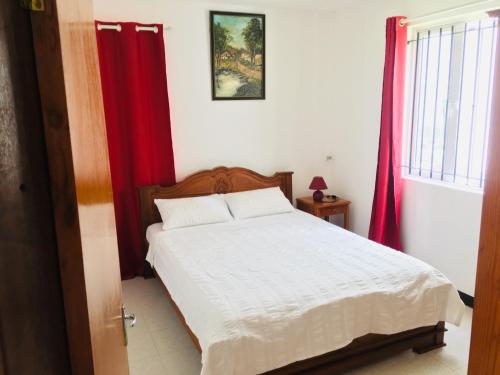 Schlafzimmer mit einem weißen Bett und roten Vorhängen in der Unterkunft Les Gentilhommieres Guest House in Trou aux Biches