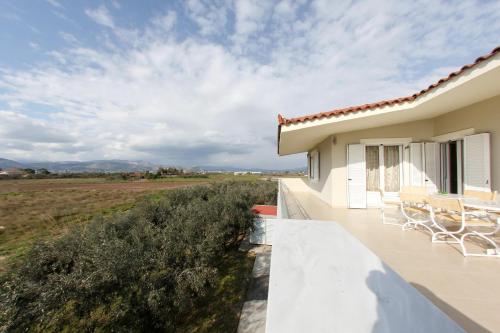 a balcony of a house with a view of a field at The Villa of the Winds in Néa Kíos