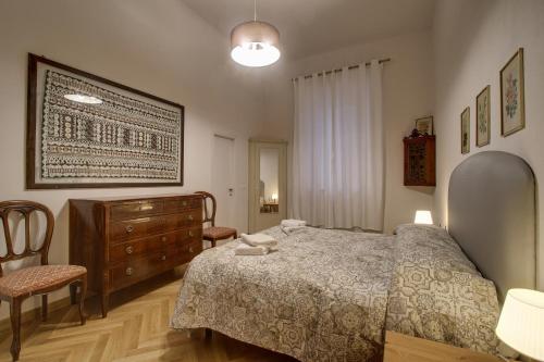 a bedroom with a bed and a dresser and chairs at Piazza Mentana Apartment in Florence