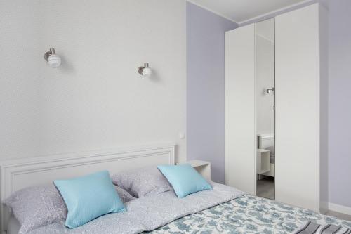 a white bedroom with blue pillows on a bed at Luxury Apartment Solvo in Gdańsk