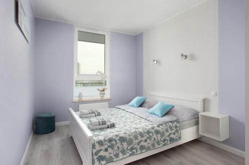 Dormitorio blanco con cama con almohadas azules en Luxury Apartment Solvo, en Gdansk