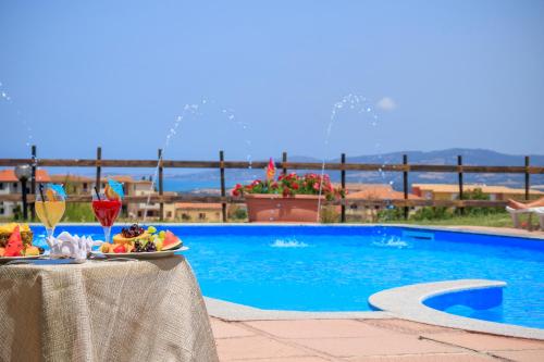 a table with a plate of food next to a swimming pool at Abbaidda Hotel in Valledoria