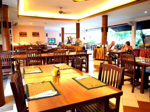 a restaurant with wooden tables and chairs and people sitting at tables at Fanari Khaolak Resort - Courtyard SHA Extra Plus in Khao Lak