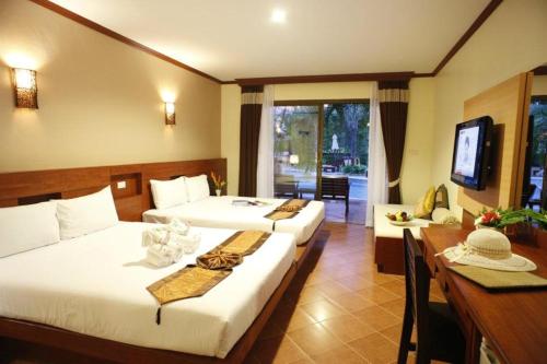 a hotel room with two beds and a table and a desk at Fanari Khaolak Resort - Courtyard SHA Extra Plus in Khao Lak