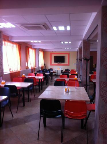 a dining room with tables and red chairs at Mereke Hotel in Ustʼ-Kamenogorsk