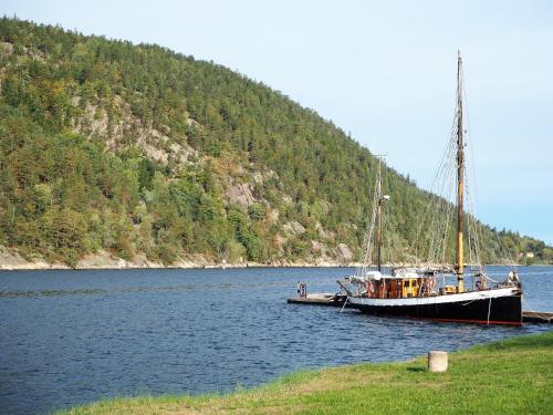 a boat sitting on the water next to a mountain at Oscarsborg Castle Hotel & Resort in Drøbak