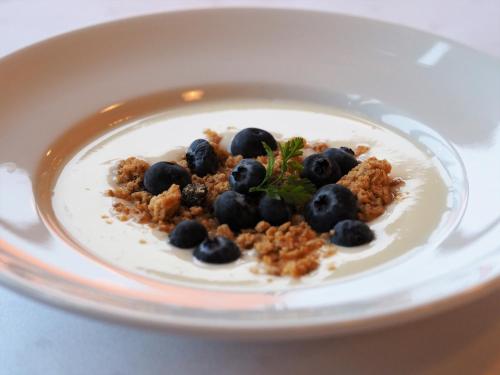 a plate of food with blueberries and granola at Oscarsborg Castle Hotel & Resort in Drøbak