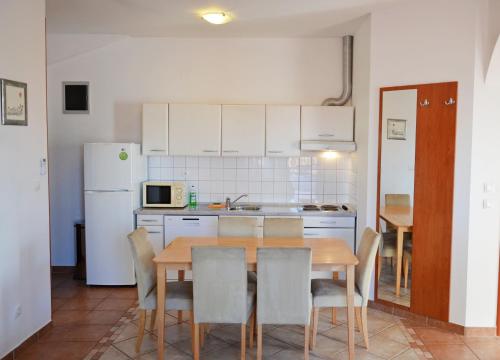cocina con mesa, sillas y nevera blanca en Apartments Pirovcanka, en Pirovac