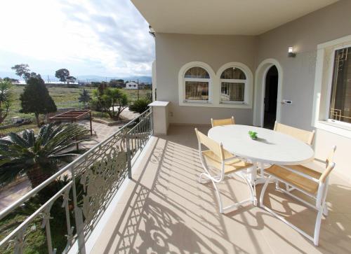 a balcony with a white table and chairs at The Villa of the Winds in Néa Kíos