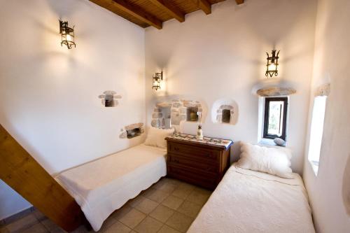 a bedroom with two beds and a dresser and a window at Arapakis Historic Castle in Pirgos Dhirou