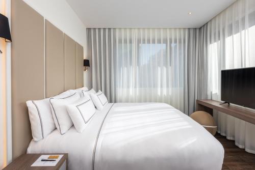 a white bedroom with a large bed and a tv at Melia Madrid Serrano in Madrid