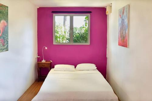 a bedroom with a purple wall and two beds at Rusty Pelican - "Goofy Gecko" Container Apt. in La Gaulette