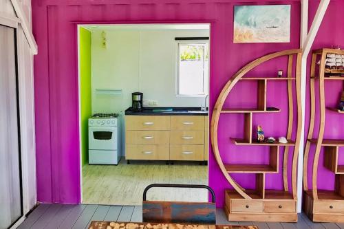 a kitchen with a pink wall and a spiral staircase at Rusty Pelican - "Goofy Gecko" Container Apt. in La Gaulette