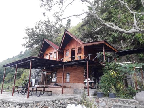 a wooden house on a hill with trees in the background at Pondok Berata Dapdap in Balige