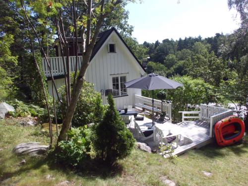 ein kleines weißes Haus mit einer Terrasse und einem Sonnenschirm in der Unterkunft Det Vita Huset in Stockholm