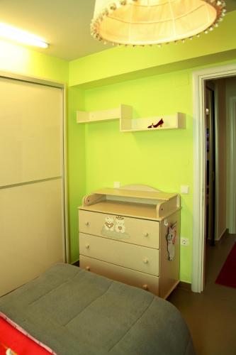 a green bedroom with a bed and a dresser at The Villa of the Winds in Néa Kíos