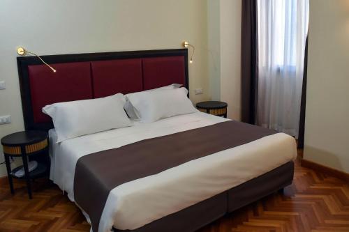 um quarto com uma cama grande e duas mesas em Torrione Hotel em Reggio di Calabria