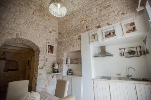 una cucina con parete in pietra e lavandino di IL TRULLO DELLA MASSAIA ad Alberobello