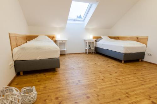 two beds in a room with wood floors and a window at Dorf Alm Ferienwohnung in Schwalmtal