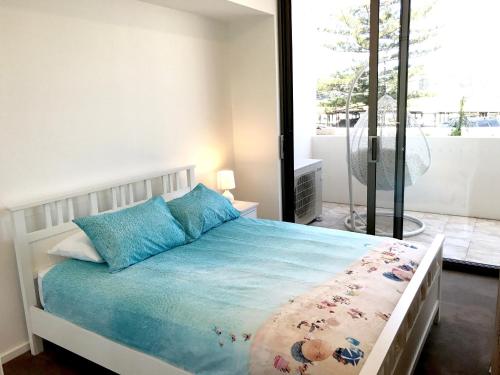 a bedroom with a bed with blue pillows and a window at Kiama Executive in Kiama