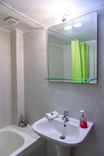 a white bathroom with a sink and a mirror at Sunrise Beachfront Apartment in Sitia