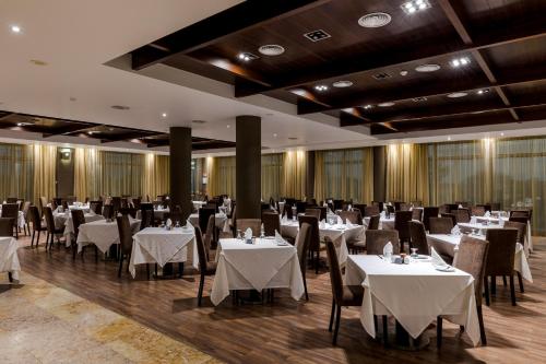 a dining room with tables and chairs with white tablecloths at Hotel Apartamento Dunamar in Monte Gordo