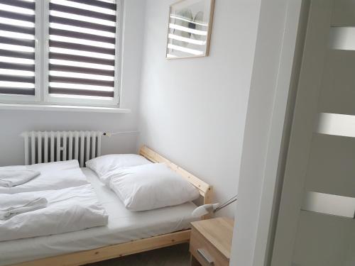 uma cama com almofadas brancas num quarto com uma janela em visit baltic - Matejki III em Świnoujście