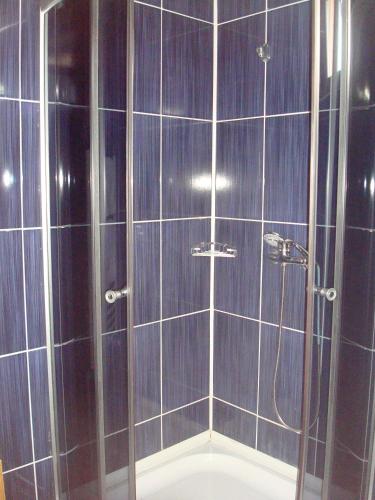 a bathroom with a shower with blue tiles at Pensiunea Doneli in Eforie Nord