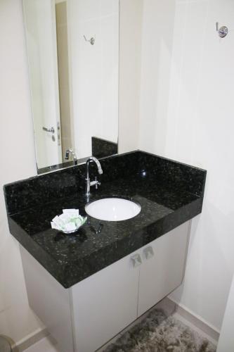 a bathroom sink with a black counter top at Blu Apart Hotel in Mogi-Guaçu