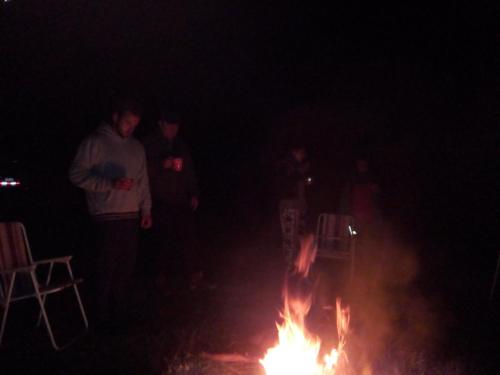 a group of people standing around a fire at night at Wayqi Wasi in Pisac