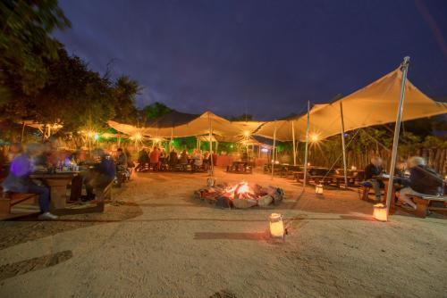 a group of people sitting around a fire under a tent at Nkambeni Safari Camp in Hazyview