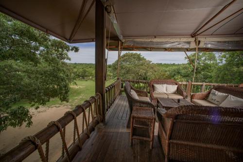 a porch with chairs and a table on a deck at Nkambeni Safari Camp in Hazyview