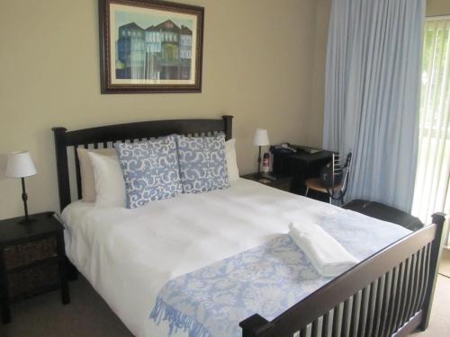 a bedroom with a large bed with blue and white pillows at Fin and Feather Guest Lodge in Boksburg