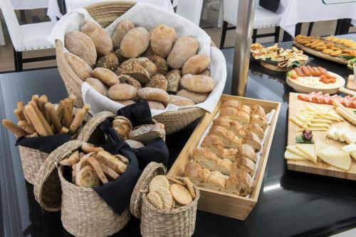 Una mesa cubierta con cestas de pan y pasteles en Hotel Cristal Marinha, en Marinha Grande