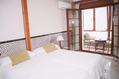 1 dormitorio con cama blanca y balcón en Vivienda Turistica Arabeluj en Güéjar-Sierra