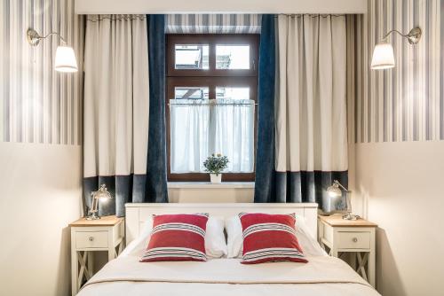 a bedroom with a bed with red pillows and a window at Sanhaus Apartments in Sopot