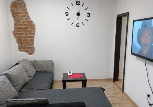a living room with a couch and a clock on the wall at Ubytovanie Queen in Nováky