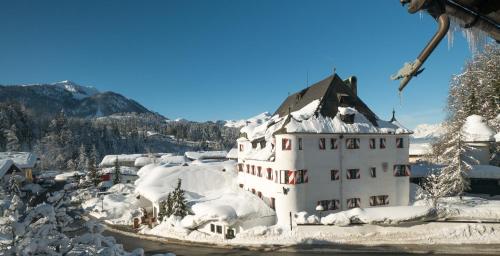 a building covered in snow on a mountain at Family Hotel Schloss Rosenegg in Fieberbrunn