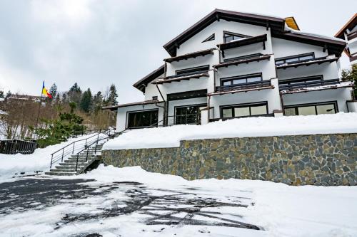 a house in the snow with a stone wall at Vila Hera Luxury in Predeal