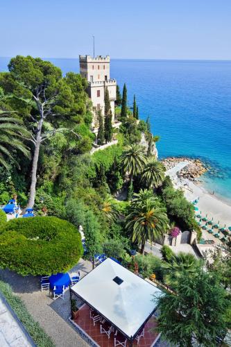 a building on a hill next to the ocean at Hotel Punta Est in Finale Ligure