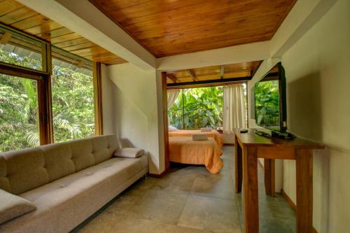 a living room with a couch and a bed and windows at Terrabambu Lodge in Mindo