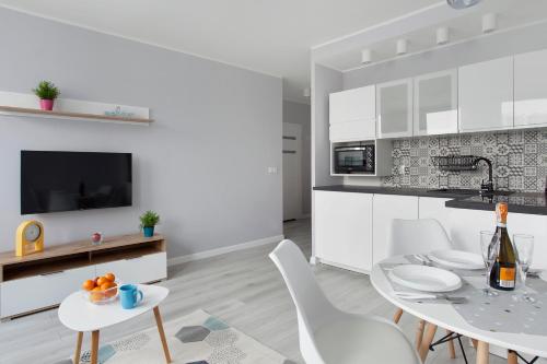 a kitchen with white cabinets and a table and chairs at Luxury Apartment Solvo in Gdańsk