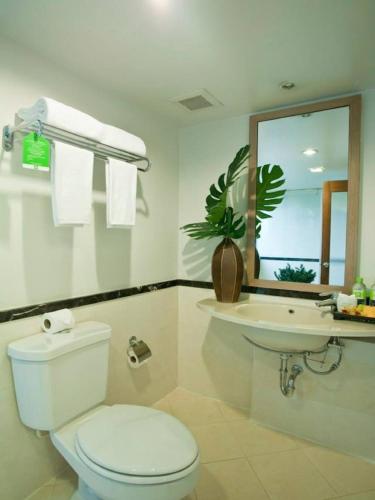 a white bathroom with a toilet and a sink at The Seasons Bangkok Huamark in Bangkok