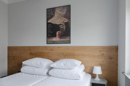 a bed with white pillows and a painting above it at MoHo XL in Wrocław